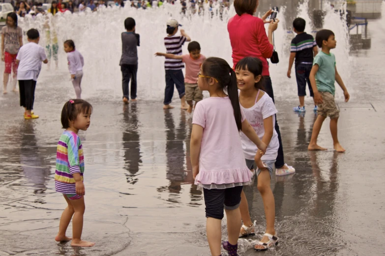 several children stand in front of a spout fountain