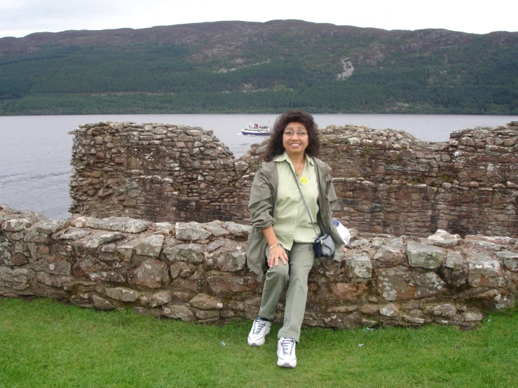 the lady is posing for a po on the stone wall