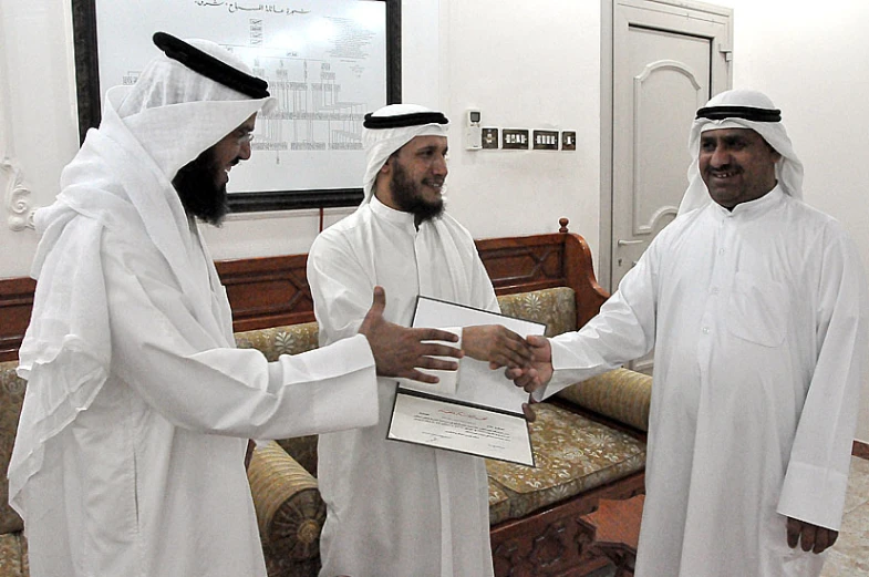 three men shaking hands in a large room