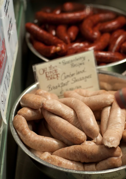 a pot full of sausages sitting next to other containers of cooked sausage