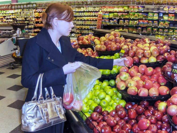 a woman is picking apples in a grocery store