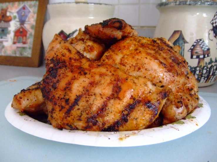 some chicken sitting on a white plate and on the counter