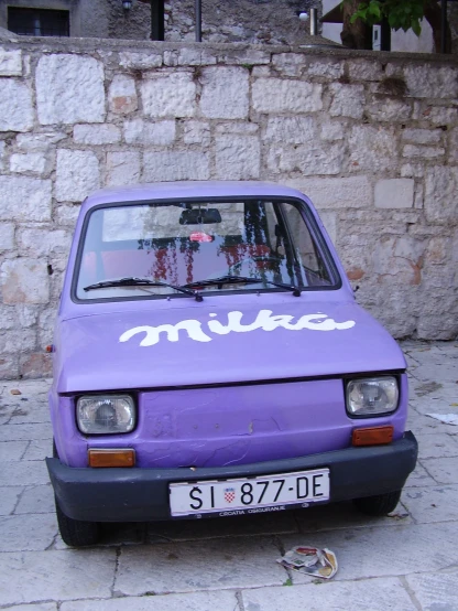 a purple car parked near a brick wall