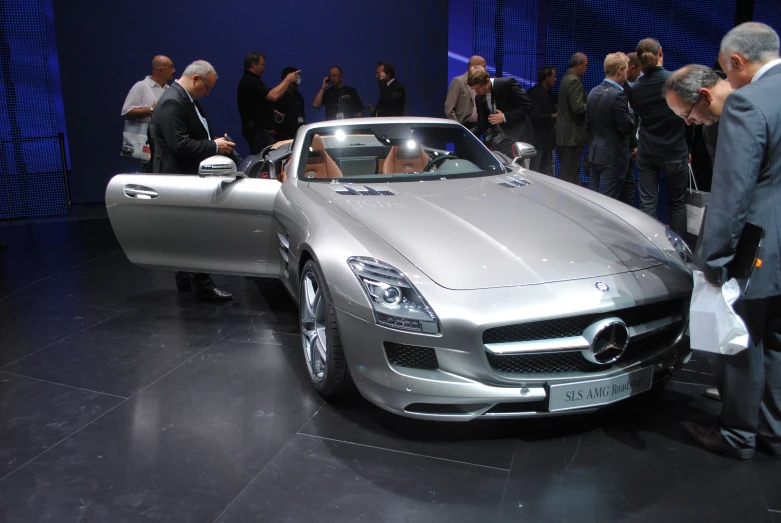 two people and a silver car parked in a show room