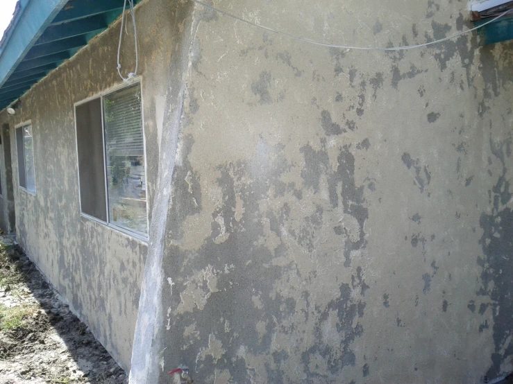 the side of a house with a dirty stucco structure