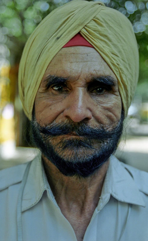 a man wearing a yellow turban stares ahead