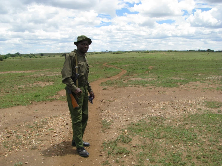 a man wearing green uniform standing in front of a field