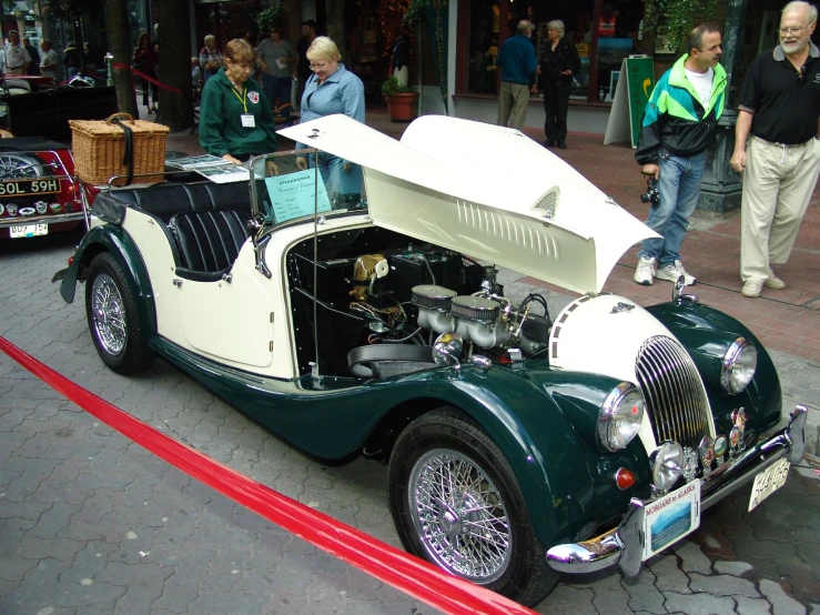 an antique model car parked with a surfboard on the hood