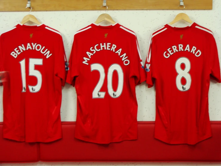 three soccer players'red uniforms hanging on a rack