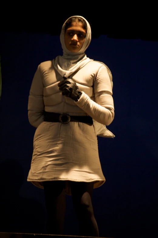 a woman in white standing in a darkened room