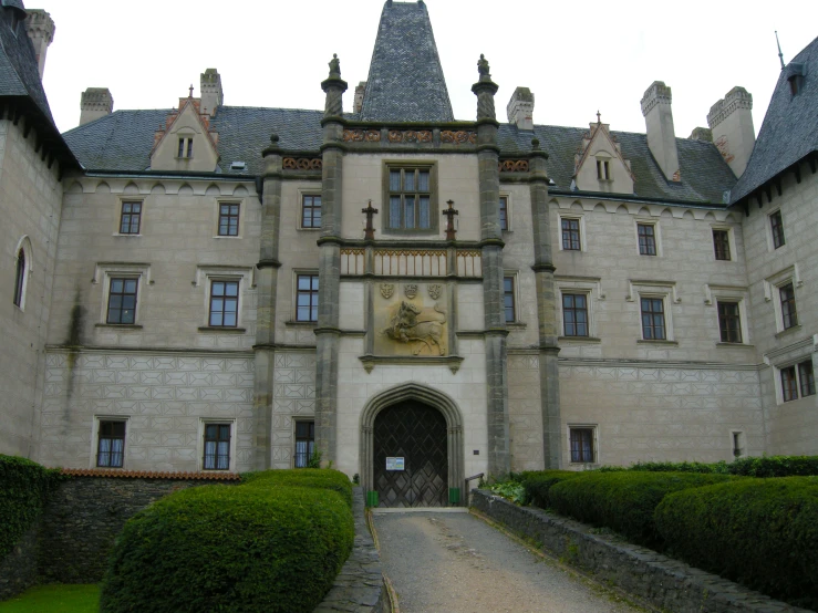 the front entrance of an old castle, with two towers and large stone windows