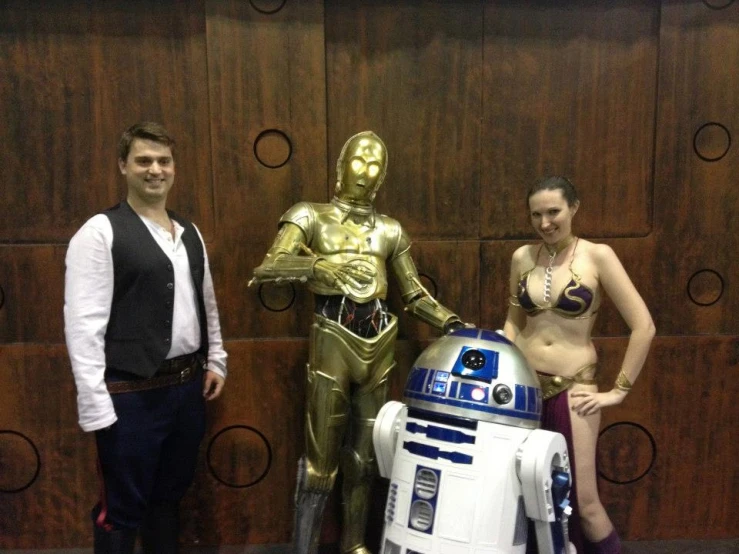 a man and woman stand with a robot at the convention