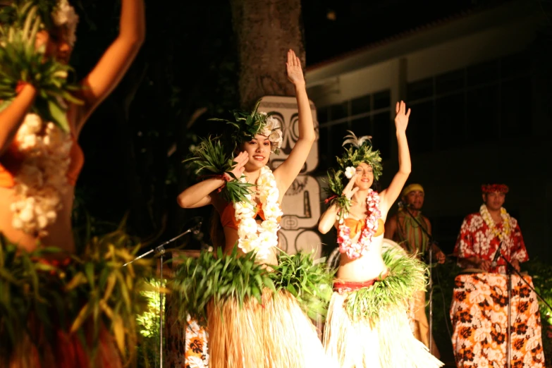 hula dancers dressed in grass skirts, performing with microphones