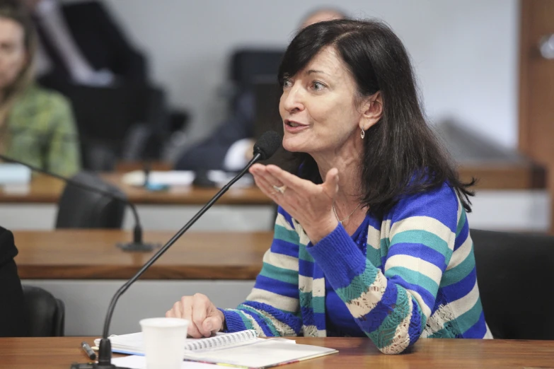 a woman sitting at a desk talking into a microphone