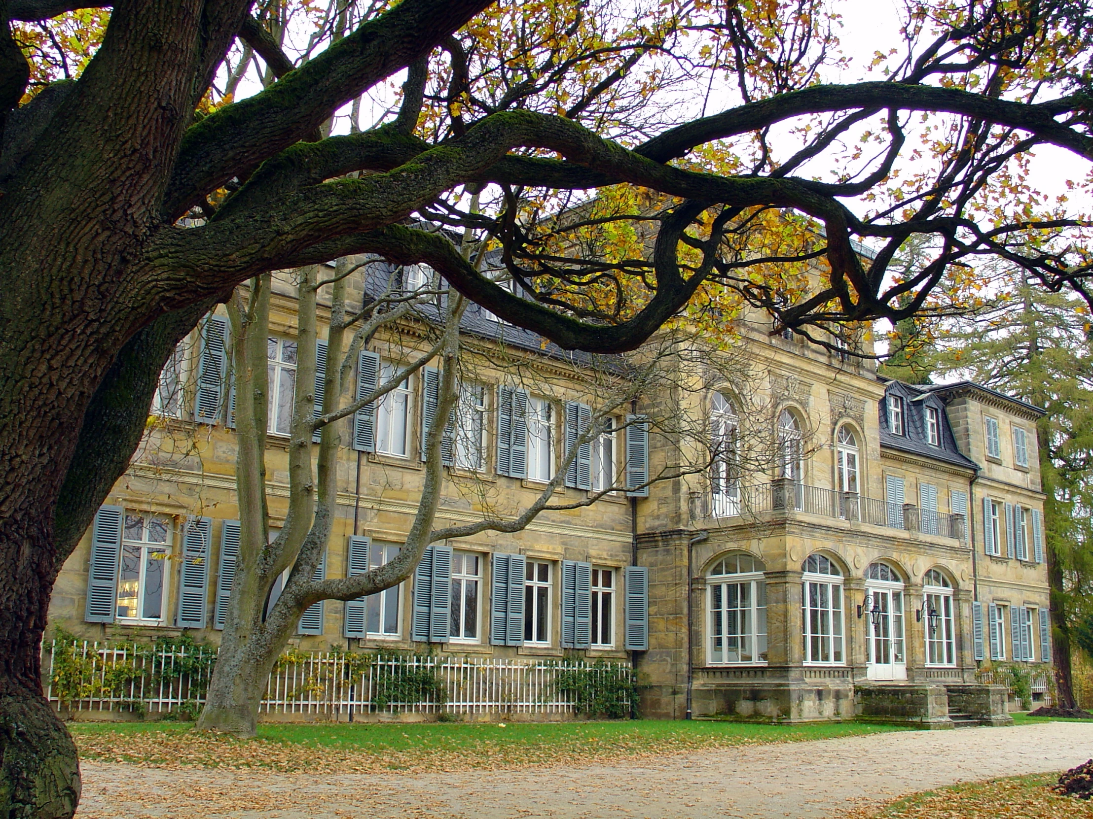 the large house has several windows and has a fence around it