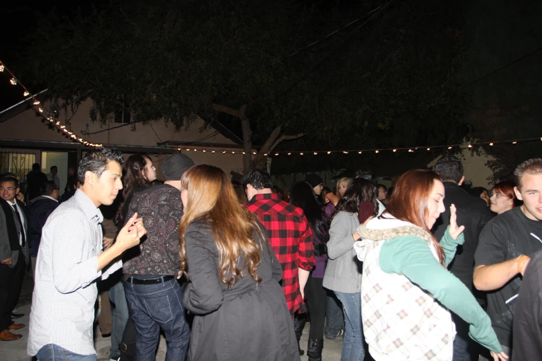 a group of people standing on a sidewalk next to a tree