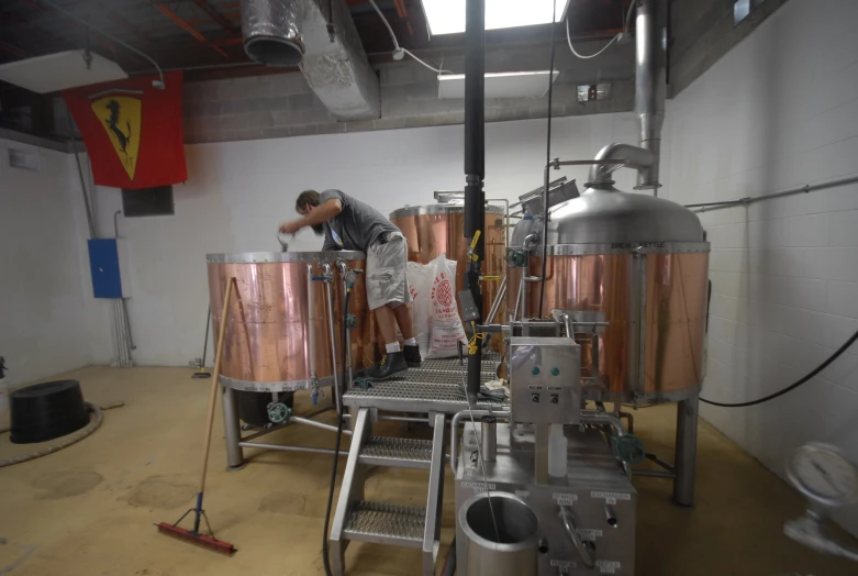 a man standing in front of many copper kettles