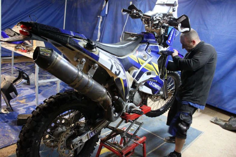 a man doing a motorcycle maintenance trick with another man standing behind