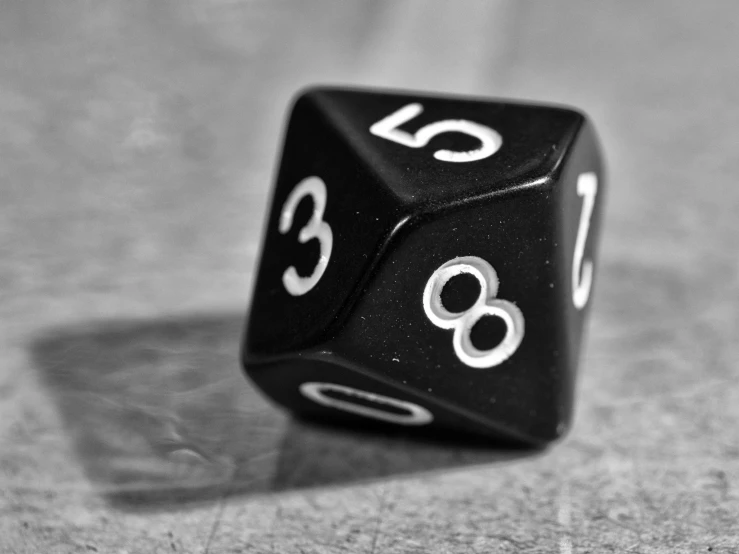a black dice with white numbers is on a gray surface