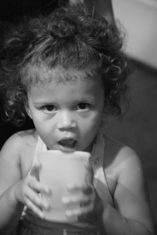 black and white po of a toddler taking a drink from a cup