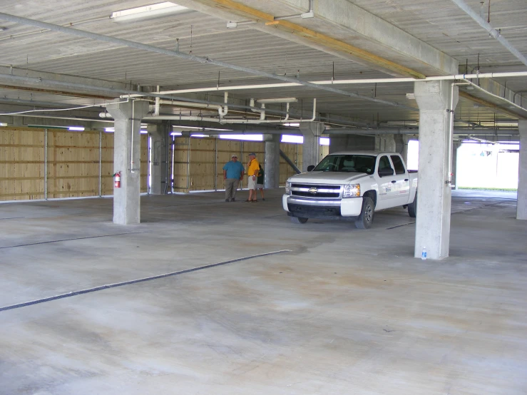 a white truck parked next to two people in a parking garage