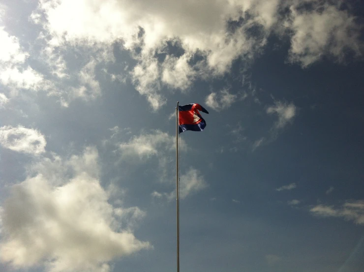 a flag on a pole under a blue cloudy sky