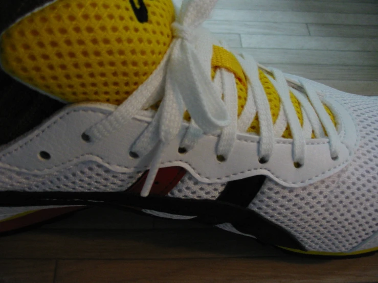 a pair of white sneakers sitting on top of a hard wood floor