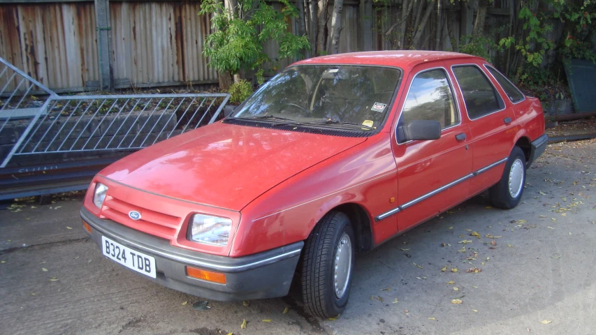 a red car parked near some bushes outside