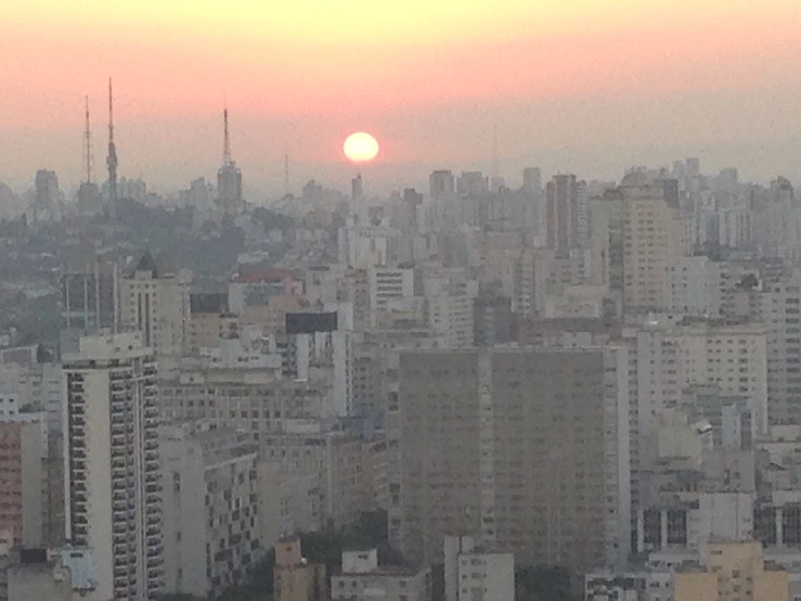 the sun is setting over the city in the distance