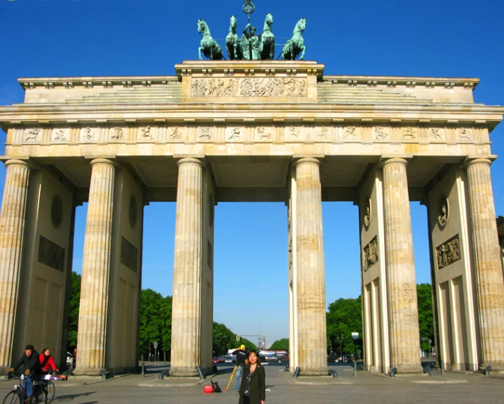 tourists walking by a large stone arch in a city