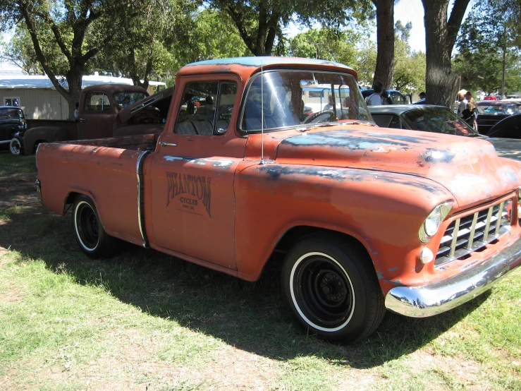 an old red truck is parked in the grass