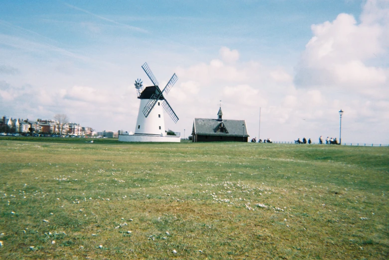 a windmill in a field next to an old barn