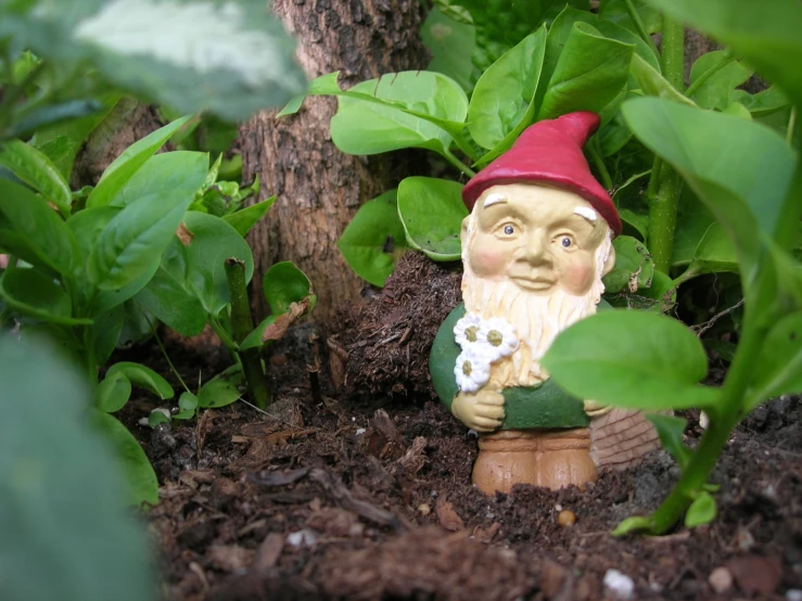 a small figurine is surrounded by greenery and flowers