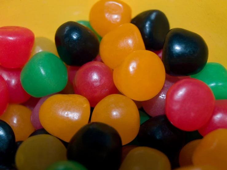 many different color candies are piled high on a yellow surface