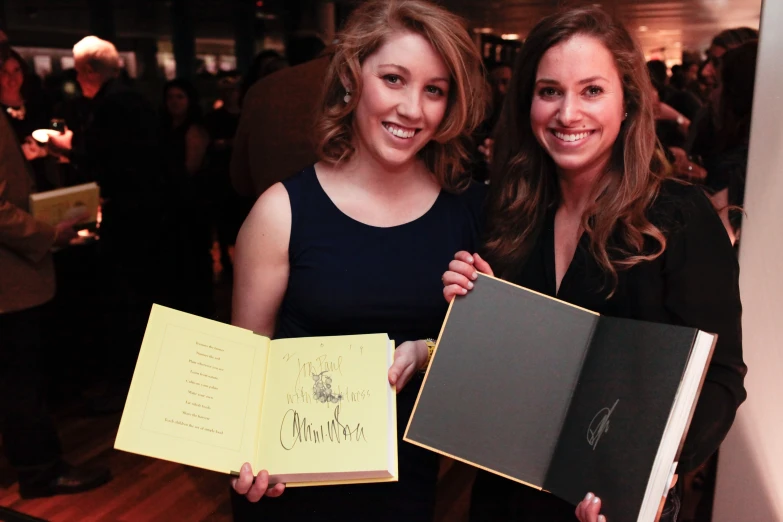 two women holding open books in the air