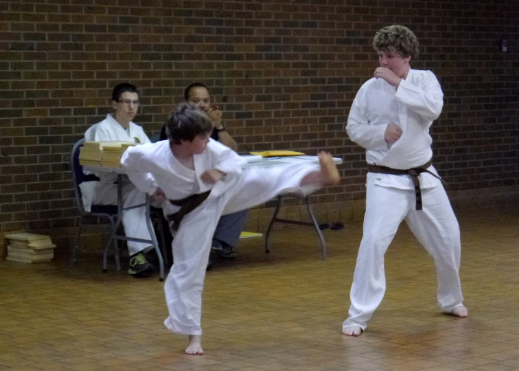 two young men in karate attire performing martial tricks