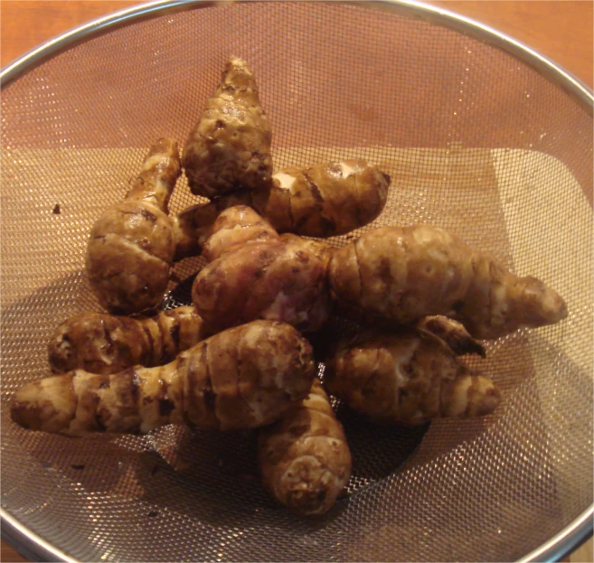 a metal bowl holds a few raw ginger stalks