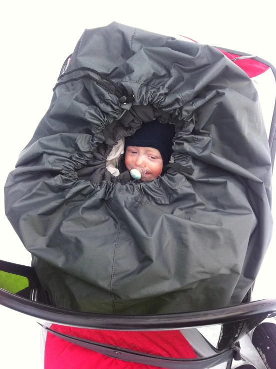 a baby laying in the top of a large black bag