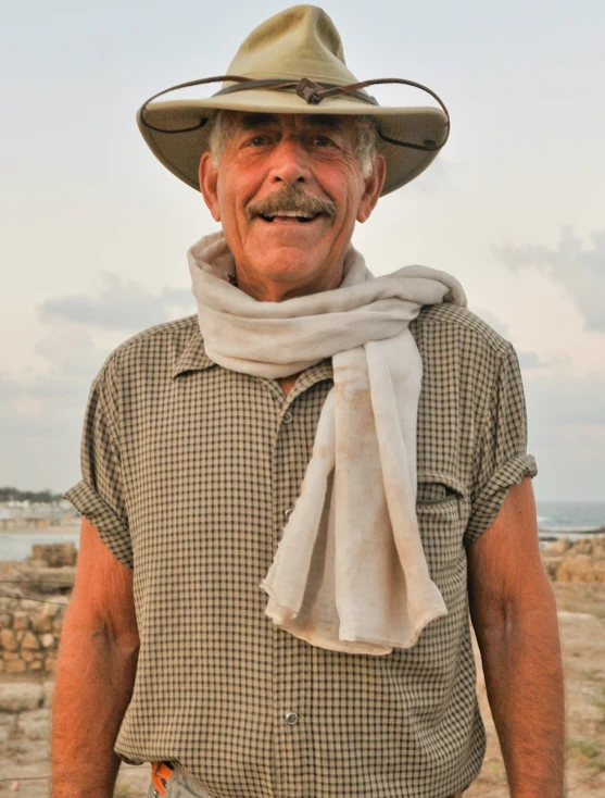 a man standing in front of the sea with his hat on