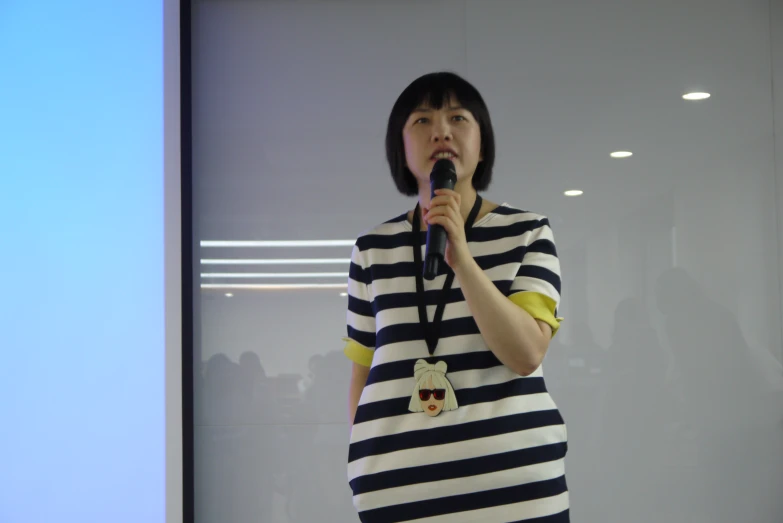 an asian lady in striped dress holding a microphone