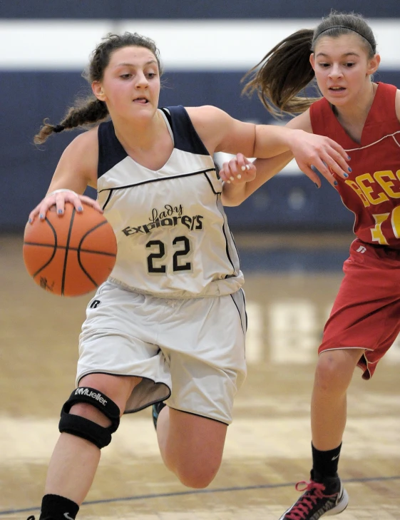 two women are going after a basketball on the court