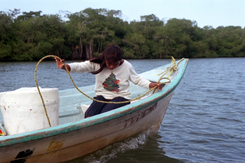 woman in white sweater in small boat with rope