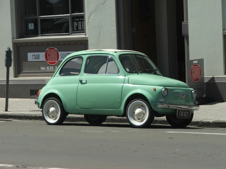the small green car is parked on the street