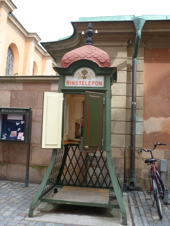 a green, ornate outdoor structure next to a bicycle