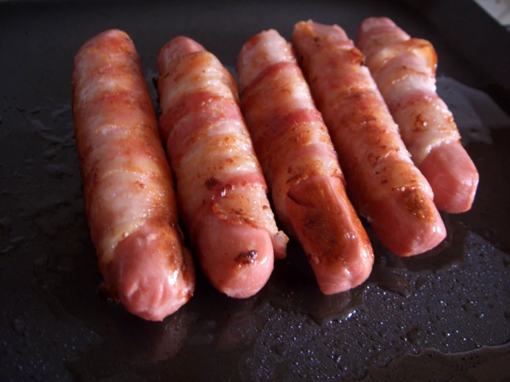 four sausages are cooked on a grill in oil