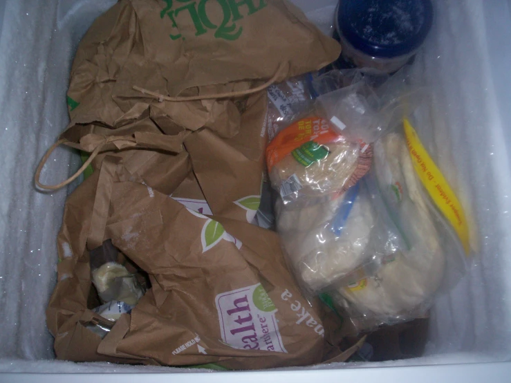 a packed refrigerator door with plastic bags and food