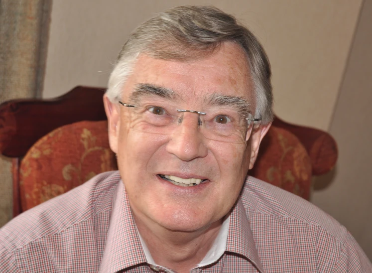 older man with glasses and plaid shirt sitting on a chair