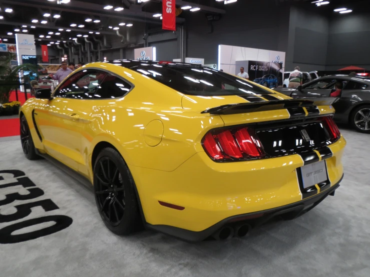 two yellow mustangs are parked in a show room