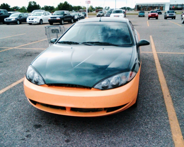 a small orange car sits in a parking lot