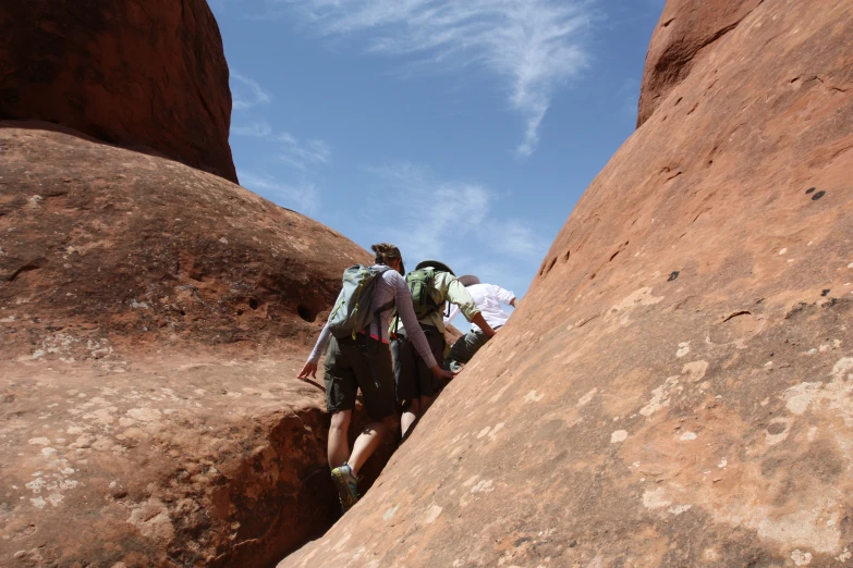 a couple of people with some hiking gear climbing some rocks